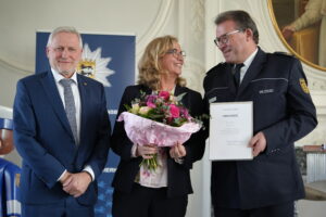 Polizeipräsident Stürmer mit der Dankurkunde des Landes, seine Ehefrau daneben mit einem Blumenstrauß. Mit auf dem Bild Staatssekretär Thomas Blenke